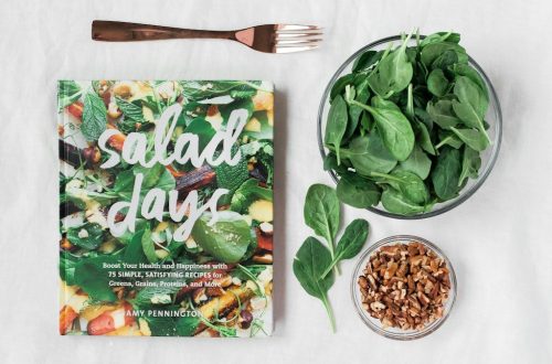 Salad day cookbook beside clear glass bowl with vegetable